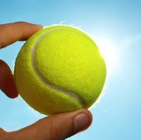 Hand holding tennis ball up to the sky